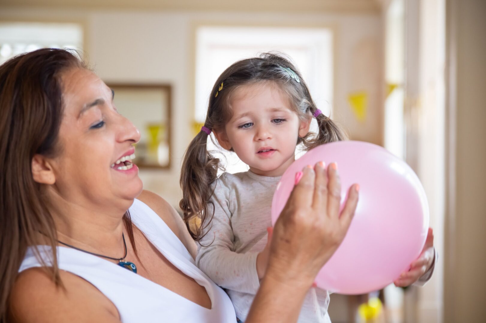 Smiling woman holding toddler and balloon.
